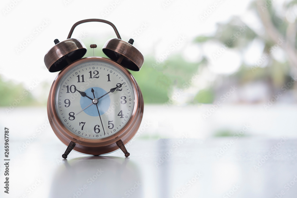 Wall mural Bronze vintage alarm clock on table bokeh background