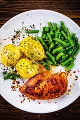 Grilled chicken fillet and vegetables on wooden table