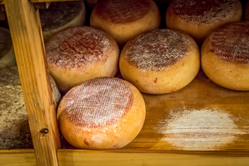 Cheese on the shelves in a cheese shop in the town of Pienza. Tuscany, Italy