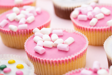 Colorful cupcakes on a pink background.