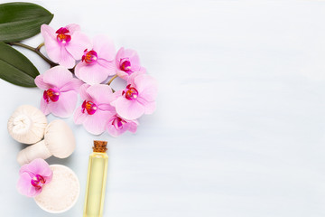 Sea salt, aromatherapy oil in bottles and orchid on vintage wooden background.