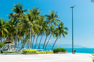 Naklejka premium Woman and man stand on tropical beach with palm and lamp in vacation