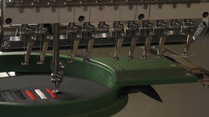 In slow motion video in a garment factory, a sewing machine embroiders various companies and...