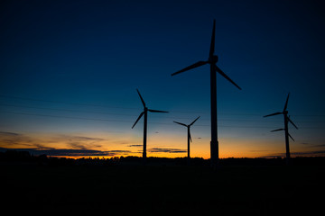 Obraz premium Power generators of windmills at shadow sunset - Wind turbine on field at sunset