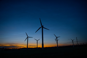 Obraz premium Power generators of windmills at shadow sunset - Wind turbine on field at sunset