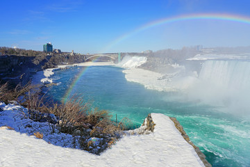 Rainbow over the Horseshoe Falls over frozen ice and snow on the Niagara River in Niagara Falls in March 2019
