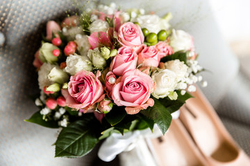 Wedding bouquet of white and pink roses on a blurred background of the bride's shoes