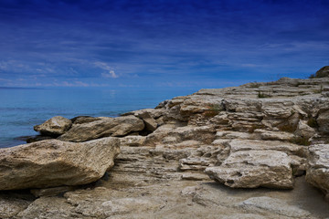 Panorama landscape scenic view of isolated deserted rocky beach with blue turquoise sea water and sky with white clouds and mountain background on beautiful and colorful Mallorca island in Spain.