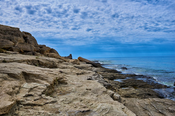 Rocky coastline with a cove and rock, split view above water surface, Mediterranean sea, Spain. Azure sea, wave and blue sky. Seascape with sea horizon and cloudy deep blue sky.