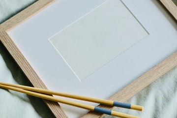 Mockup-template. Photo frame in bed. Wooden chopsticks on frame, with white copy space, cozy feeling ideal for Asian food/beverage shoot-out.