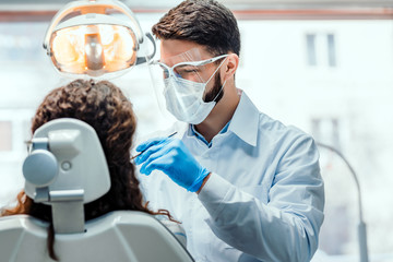 Dentist working in dental clinic with patient in the chair. - obrazy, fototapety, plakaty