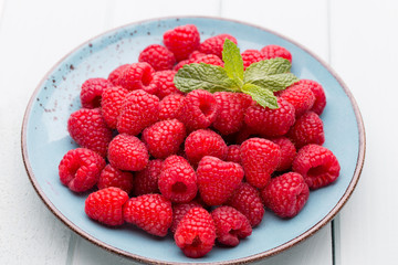 Fresh raspberries in a plate on a  vintage background.