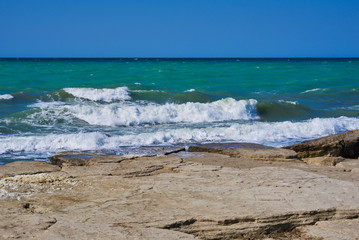 Summer landscape. Rocky coastline with a cove and rock, split view above water surface, Mediterranean sea, Spain. Azure sea, wave and blue sky. Seascape with sea horizon and clear deep blue sky.