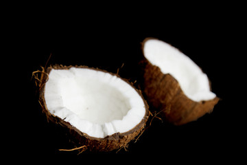 ripe coconut is broken into two halves isolated on a black background close-up. the insides of the tropical palm fetus