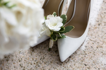 Bride's shoes with boutonniere on a blurred background of a wedding bouquet