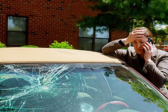 Woman making a phone call next to damaged car after a car accident