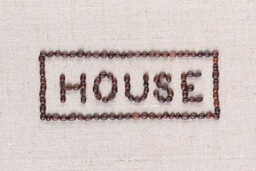 House sign from coffee beans isolated on linea texture, shot close up.
