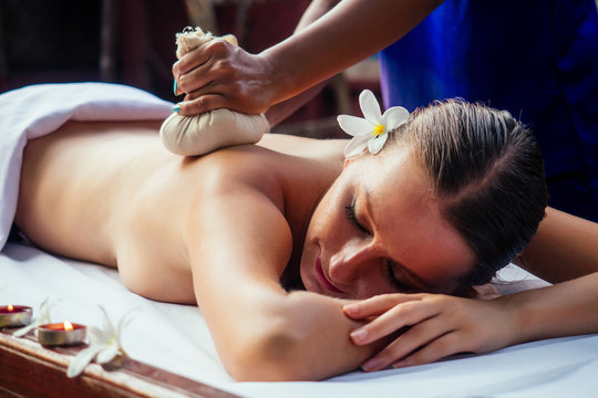 Portrait of young beautiful woman lying on a wooden table in spa environment flowers and candles