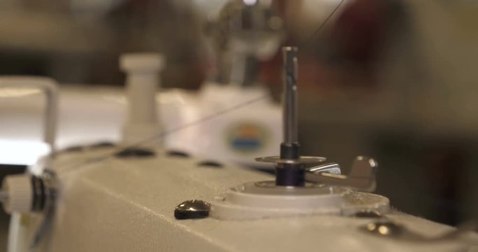 In slow motion video in a garment factory, a sewing machine embroiders various companies and engravings. Concept of: Automated work, Sewing machine, Engraving, Thread, Fabric, Needle.