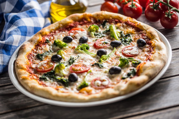 Irtalian pizza with broccoli spinach tomatoes olives and mozzarela or parmesan cheese. Mediterranean vegetarian meal