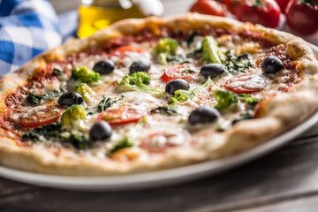 Irtalian pizza with broccoli spinach tomatoes olives and mozzarela or parmesan cheese. Mediterranean vegetarian meal