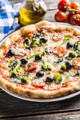 Irtalian pizza with broccoli spinach tomatoes olives and mozzarela or parmesan cheese. Mediterranean vegetarian meal