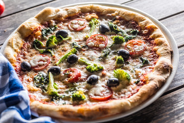 Irtalian pizza with broccoli spinach tomatoes olives and mozzarela or parmesan cheese. Mediterranean vegetarian meal