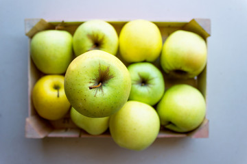 Green apples in a wooden crate. Concept- fresh organic fruit, healthy food from garden. Selective focus.