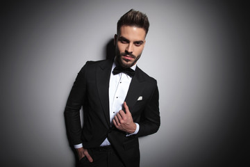 handsome businessman in black tuxedo adjusting his suit