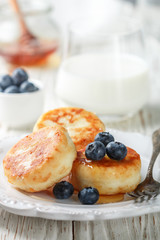 Cottage cheese pancakes, syrniki, curd fritters with fresh berries blueberry and honey in a white plate. Gourmet Breakfast. Selective focus
