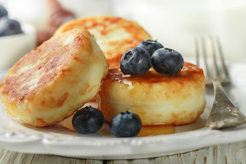 Cottage cheese pancakes, syrniki, curd fritters with fresh berries blueberry and honey in a white plate. Gourmet Breakfast. Selective focus