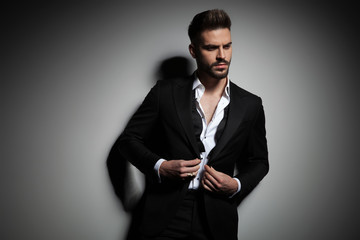 elegant man in black tuxedo buttoning his suit