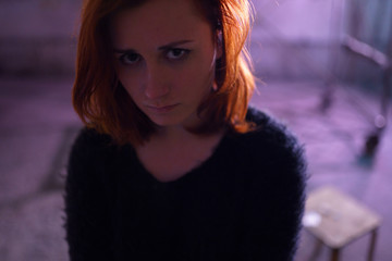 Face portrait close up of drug addiction redhead caucasian white young woman wearing black sweater, skirt and chocker with syringe and pills in the background - Anxiety, depression and danger feeling