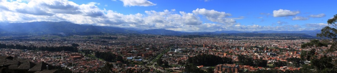 Panoramic view of a large city, Cuenca, with mountains and clouds in the background