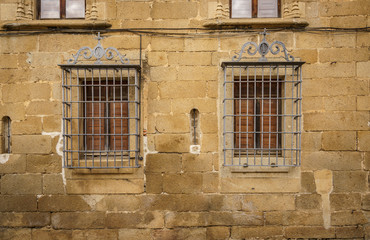 Fototapeta na wymiar Window with bars on a stone facade in Casa del Doctor Trujillo, and old medieval palase in Plasencia, Esxtremadura, Spain.