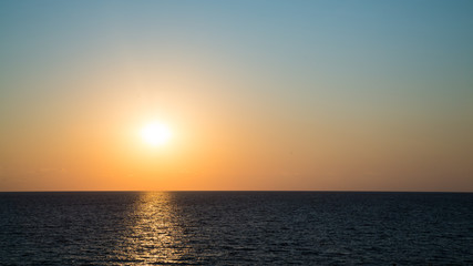 Naklejka na ściany i meble The setting sun and clear sky above the waters of the Black Sea