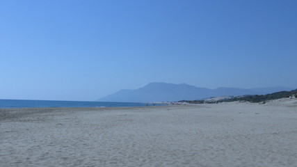 people walk along the beach along the sea enjoying the sun, the wave and the sound of water