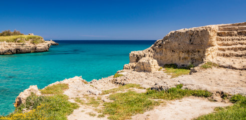 The important archaeological site and tourist resort of Roca Vecchia, in Puglia, Salento, Italy. Turquoise sea, blue sky, rocks, sun, lush vegetation in summer. Terrace on the sea