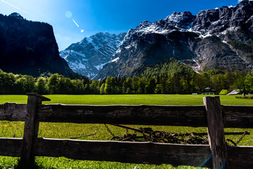Fototapeta na wymiar glade at the Koenigssee lake in the Alps, in Bavaria, view of the spring mountains, green trees and snow on the peaks