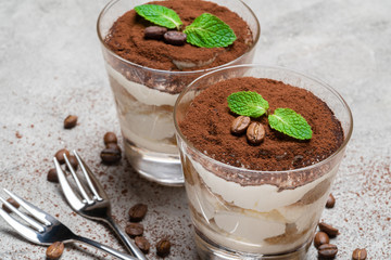 two portions Classic tiramisu dessert in a glass on concrete background