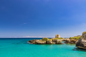 Fototapeta na wymiar The important archaeological site and tourist resort of Roca Vecchia, in Puglia, Salento, Italy. Turquoise sea, clear blue sky, rocks, sun, in summer. Messapic walls and ruins of the watch tower