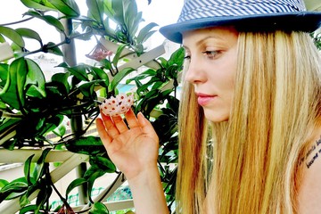 beautiful girl in a hat looks at a flower