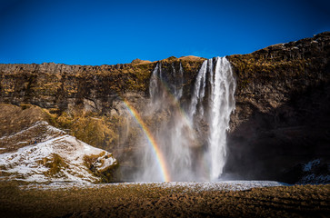 Fototapeta premium Seljalandsfoss, a majestic and powerful waterfall in Iceland in a sunny spring day with a raibow