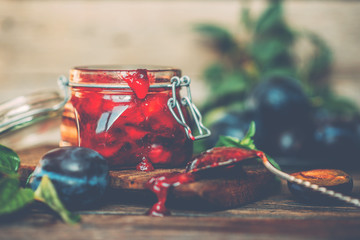 Obraz na płótnie Canvas Homemade plum jam and fresh plum fruit on a old wooden table. Autumn vegetarian, vegan food cooking.