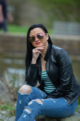 Brunette in sunglasses and black sits and enjoys the sun