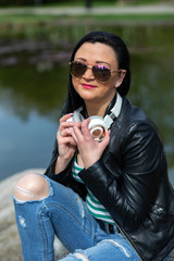 Brunette in sunglasses sits and listens to music in headphones