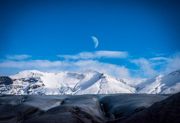Huge majestic glacier's icy surface by snowy mountain in Iceland