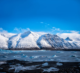 Huge majestic glacier's icy surface by snowy mountain in Iceland