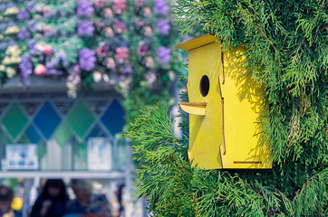 Wooden yellow birdhouse on a tree. House for birds handmade.