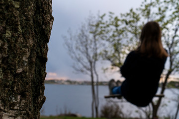 Girl swings under a tree looking out on the shore of Norway.